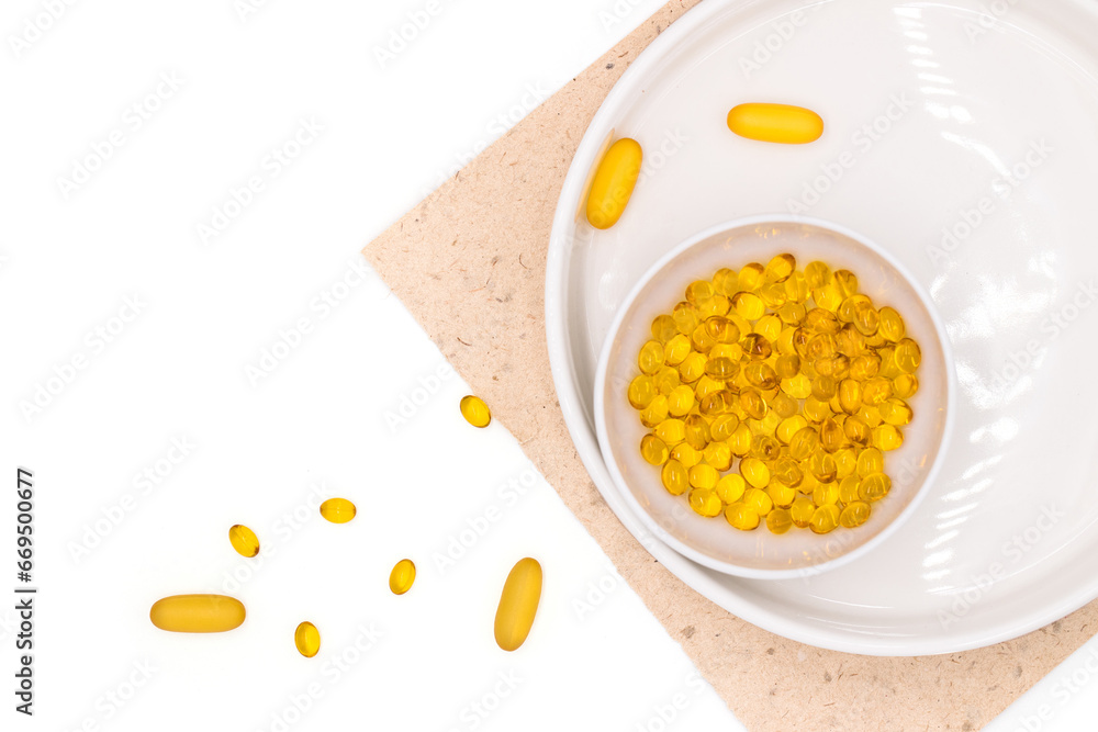 Capsules of vitamins and omega 3, oils for healthy lifestyle and skin care, on white background in white cup, flat lay with copy space, top view Capsules of vitamins and omega 3, oils for healthy lifestyle and skin care, on white background in white cup, flat lay with copy space, top view