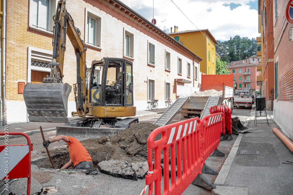 Construction Area with Operator digging with red safety barriers and excavator