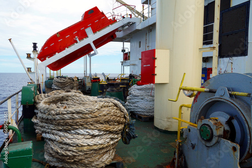 Foto Orange free fall lifeboat in the stern part of the vessel is secured on white launching ramp and ready to launch and abandon ship with crew during emergency situation