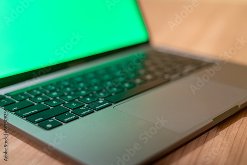 A MacBook Pro with green screen on a wooden desk