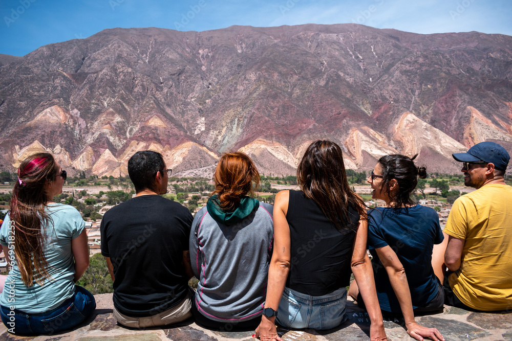 Amigos sentados en el mirador de Maimará admirando los cerros coloridos - obrazy, fototapety, plakaty 