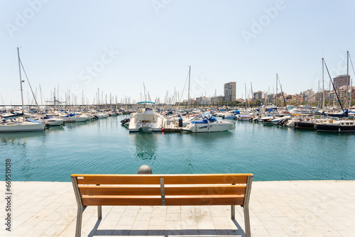 Marina with yachts in Alicante  Spain. Empty bench with view on marina bay  sunny day.