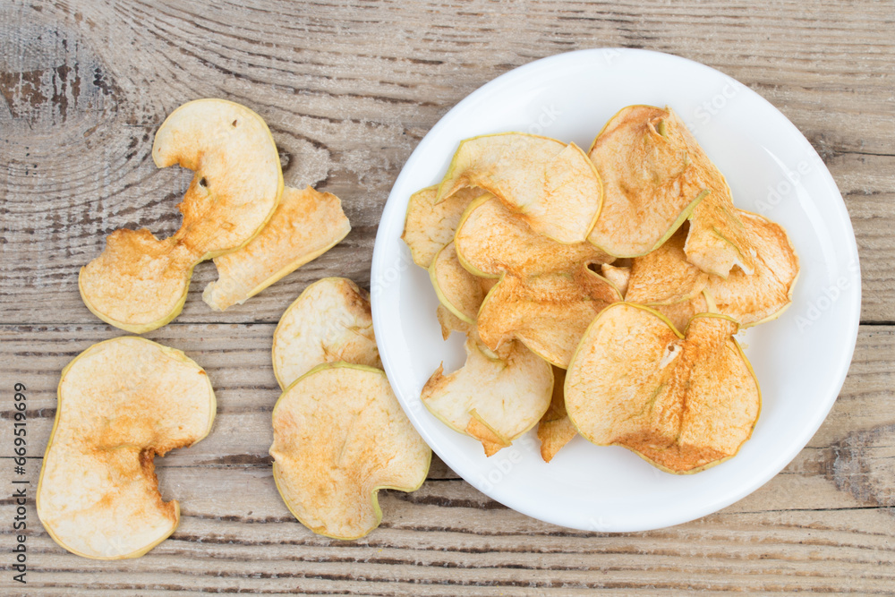 Sliced, dried apples in a plate isolated on wooden background. Homemade organic apple. Sliced, dried apples in a plate isolated on wooden background. Homemade organic apple.