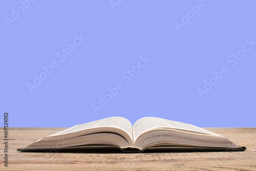 open book. Composition with hardback books, fanned pages on wooden deck table and purple background. Books stacking. Back to school. Copy Space. Education background.