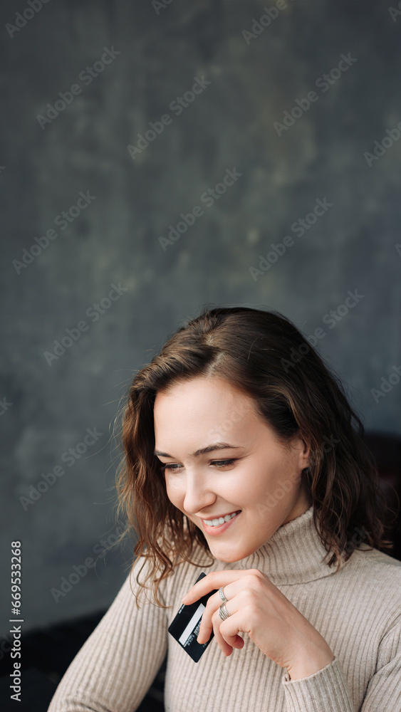 Obraz premium Convenient Online Shopping. Young Woman with Credit Card and Laptop Engages in E-commerce. Young woman holding credit card and using laptop computer. Online shopping concept.