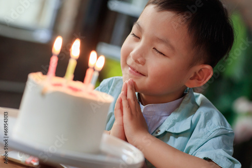 A little boy wishing on a birthday cake photo
