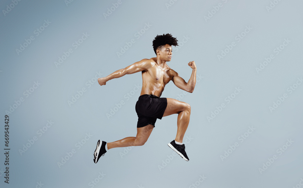 Athletic fit man sprinting and leaping forward on blue background