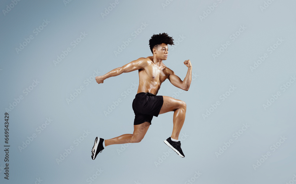 Athletic fit man sprinting and leaping forward on blue background Athletic fit man sprinting and leaping forward on blue background