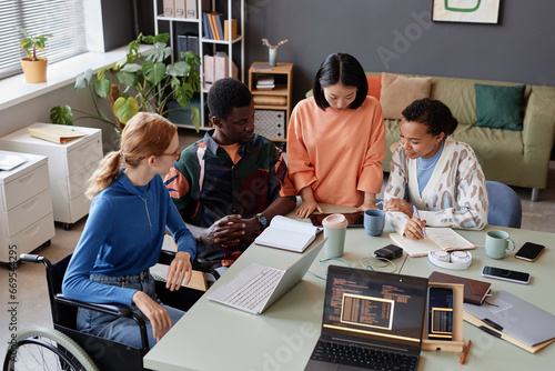 High angle portrait of young diverse team looking at digital tablet screen in IT department office photo