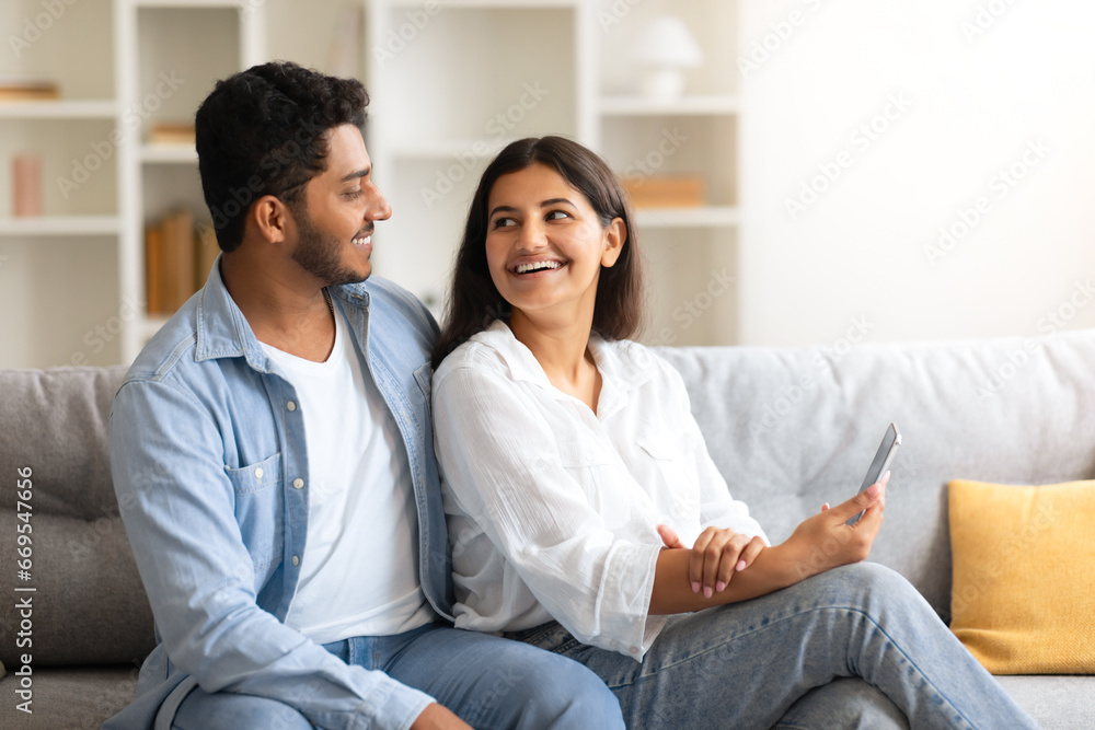 Young loving Indian couple sharing a joyful moment with smartphone at home Young loving Indian couple sharing a joyful moment with smartphone at home
