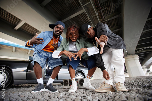 Fotografie African American boy band consisting of three hip hop performers bending over gr