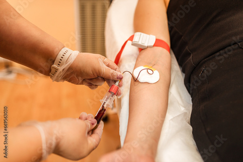 A nurse takes a blood sample from a girl's vein. © Shkriabii