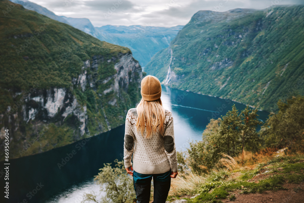 Woman traveling in Norway alone sightseeing Geiranger fjord view adventure lifestyle vacations outdoor scandinavian trip healthy lifestyle eco tourism - obrazy, fototapety, plakaty 