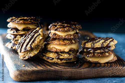 Stacks of chocolate and caramel lace cookies, against a dark background.
