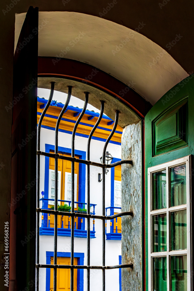 Historic colonial style house seen through the window of a church in the city of Mariana in the state of Minas Gerais