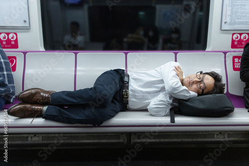 A middle-aged man sleeping in a seat in a subway car photo