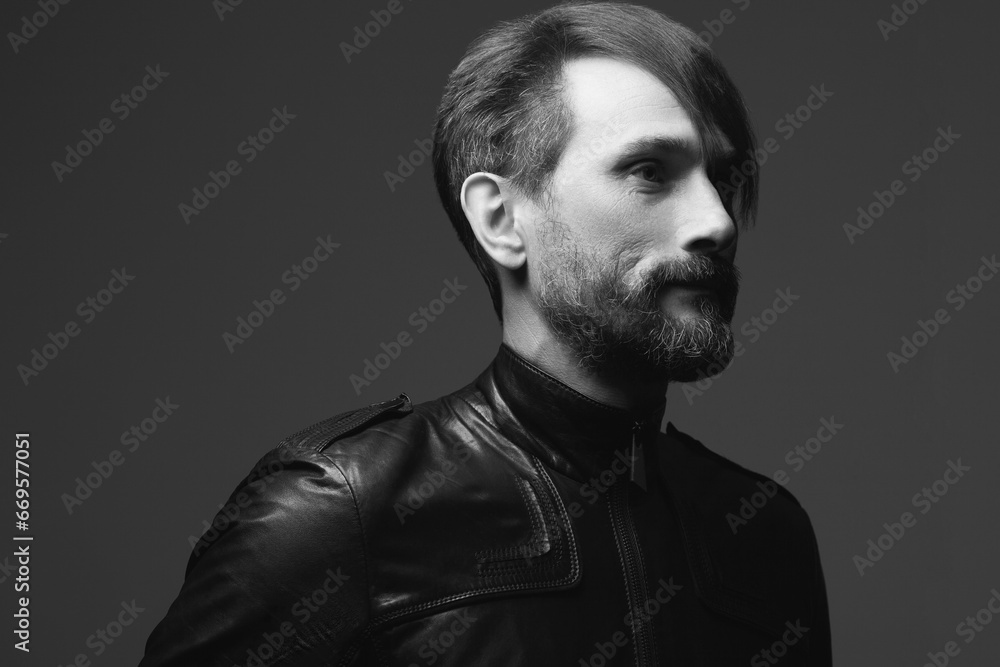 Rock star concept. Profile portrait of fashionable handsome mature biker in leather jacket over dark gray background. Close up. Copy-space. Retro style. Black and white studio shot