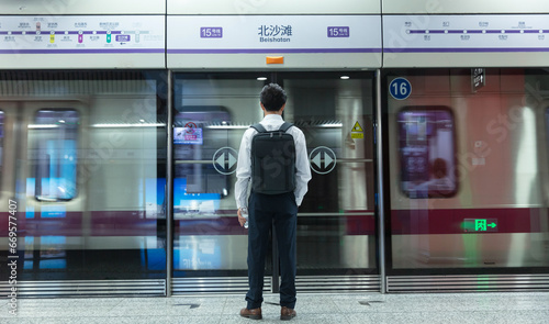 The back of a middle-aged man waiting for a bus in a subway platform photo