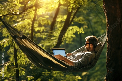 portrait of a European man lying in a hammock with a laptop in nature. remote work photo