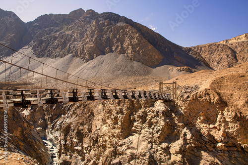 Suspension bridge on way to Shimshal village. Rocky Karakoram mountains. 