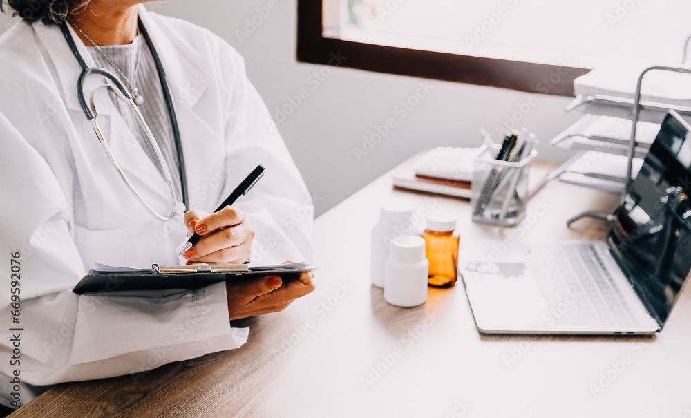 Shot of attractive female doctor working with her computer in medical consultation. Shot of attractive female doctor working with her computer in medical consultation.