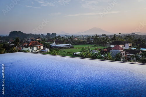 Blue swimming pool in hotel rooftop with beautiful mountain and rice paddy fields view in the morning. Swimming pool and relaxing area in the apartment. Concept for summer holiday.