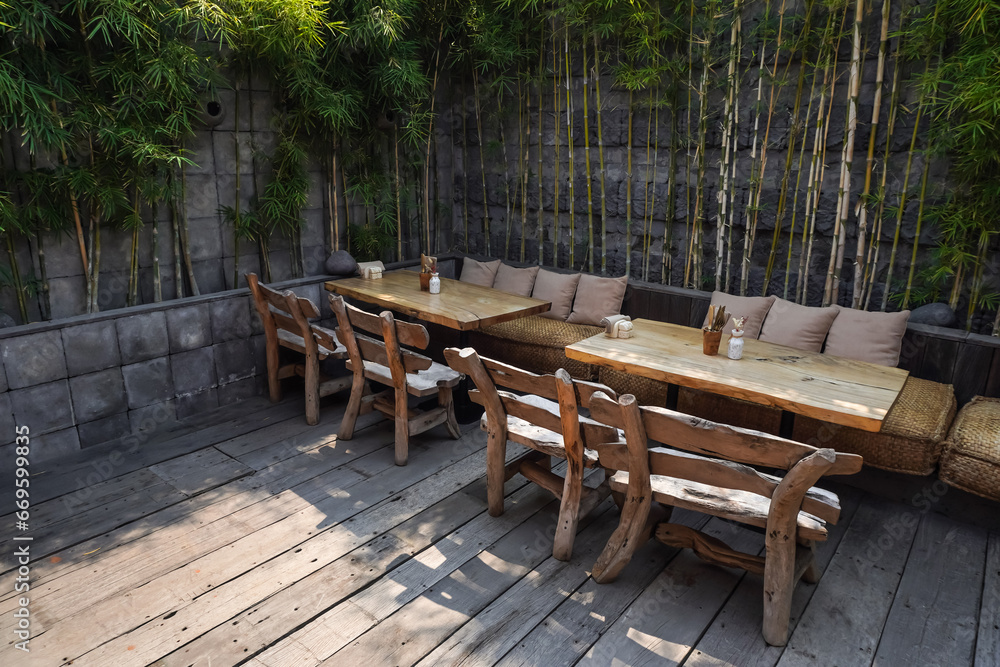 Outdoor Cafe tables and chairs set made of wood and rattan. Natural interior design concept for tropical hotel, resort, villa, restaurant and cafe. Burlap sackcloth covered sofa and square pillows.