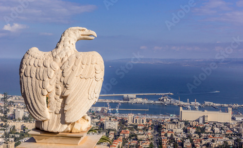 The statue of eagle on the fence at Bahai garden with the view on the Israeli city of Haifa, port, and Mediterranean sea. photo