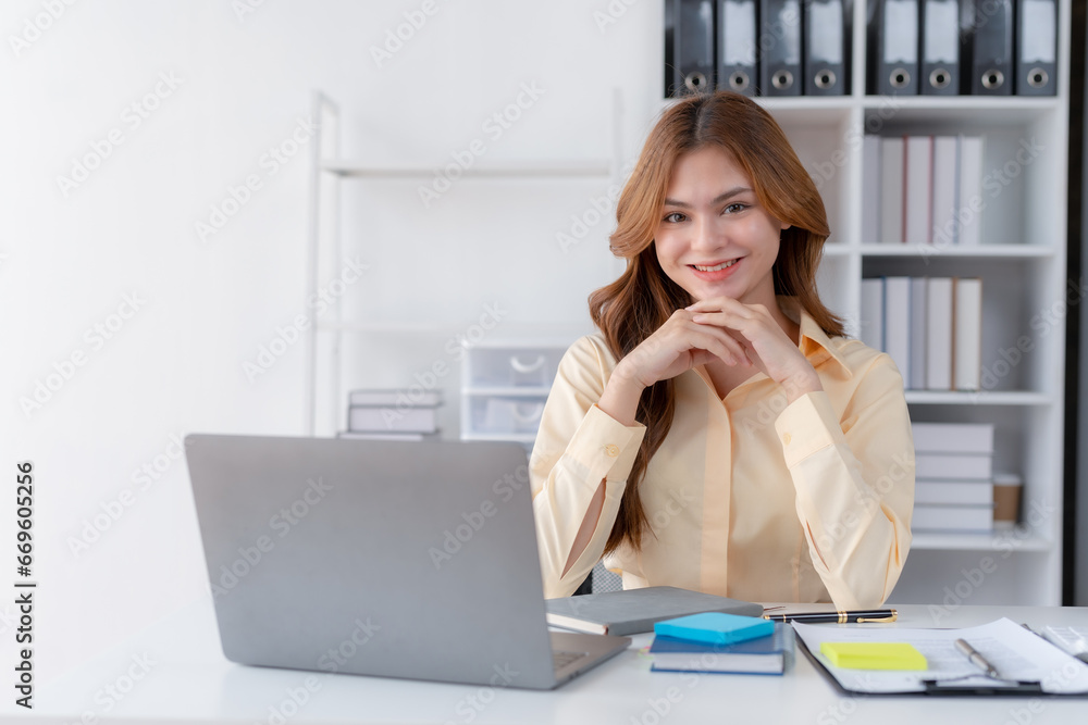 Business woman sitting with laptop and computer while doing some paperwork at the office. Looking at camera. Business woman sitting with laptop and computer while doing some paperwork at the office. Looking at camera.