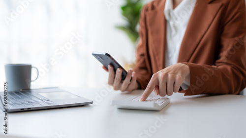 Close-up of businesswoman hands using a calculator to check company finances and earnings and budget. Business woman calculating monthly expenses, managing budget, papers, loan documents, invoices.