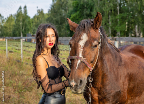 Beautiful young caucasian woman standing near the horse.