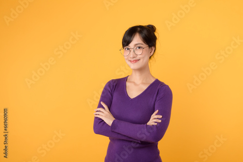 An young executive woman 30s wearing purple shirt and eyeglasses radiating confidence and joy in a corporate isolated on yellow background. Positive vibes and professionalism in action.