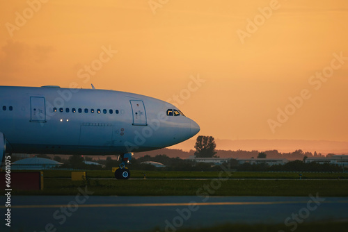 Airplane taxiing to runway for take off. Airport at golden sunset..