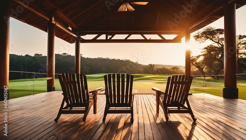 Three armchairs on wooden veranda at resort: Tranquil sunrise view over golf course