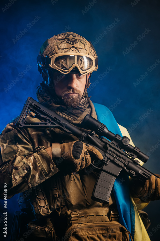 A man in a tactical military uniform with a weapon. Filmed in the studio. Explosion, smoke and fiery sparks on a dark background. The concept of military affairs. Computer games.