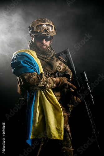 Private security contractors  elite special forces  Ukrainian soldier with full protection and Ukrainian flag in a combat zone. The concept of a strong country and invincible people.