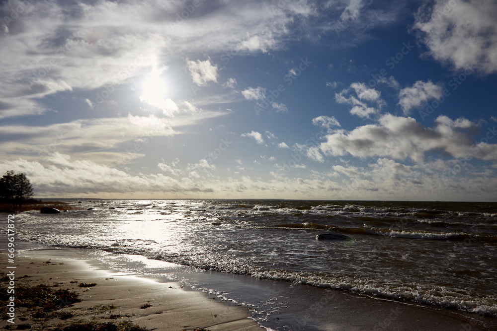 Windy day on the seashore with waves on the sea and cloudy sky above, selective focus