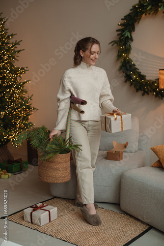 Fotografie Young stylish girl packing gifts for Christmas in a cozy home interior