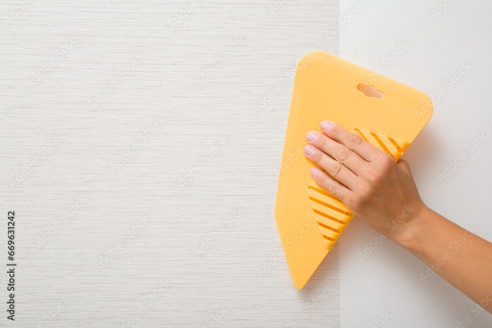 Young adult woman hand using yellow plastic spatula and smoothing
