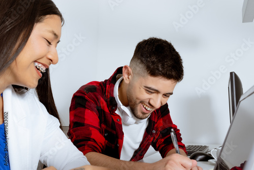 Young man and young woman laugh knowingly at workplace. photo