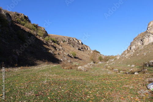 A grassy area with rocks and a hill in the background © parpalac