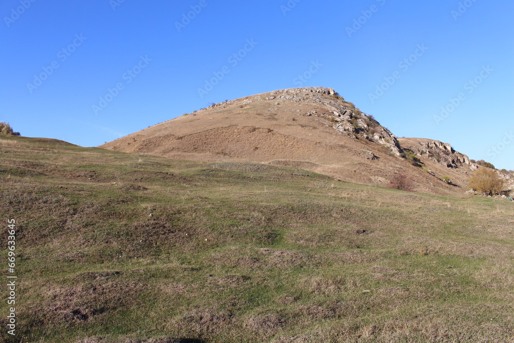 A grassy hill with a hill in the background A grassy hill with a hill in the background