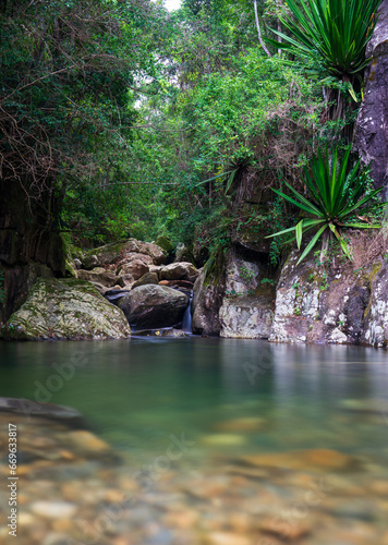 Tranquil Rainforest Scene with Silky River Flowing Through Rounded Rocks