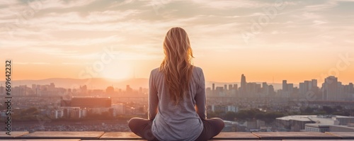 Portrait of a woman meditating on a deck overlooking a city at golden hour