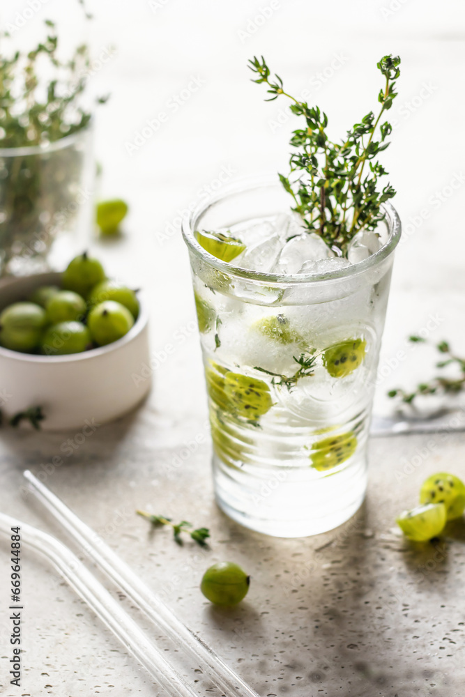 Glass of refreshing iced detox drink with gooseberries and thyme. Infused water or berry cocktail Glass of refreshing iced detox drink with gooseberries and thyme. Infused water or berry cocktail