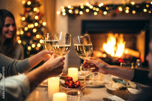 Happy friends having fun and toasting sparkling wine glasses close-up against burning fireplace background. Christmas celebration