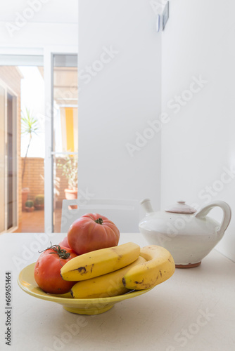 bananas and tomatoes in the fruit bowl. on the kitchen table in the morning