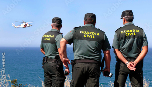 Three guards observe a rescue, rescue at sea, missing man, man now in the sea, rescue helicopter photo