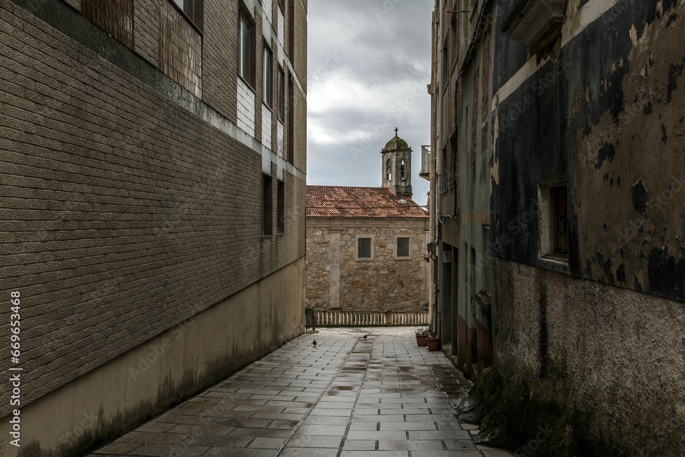 An old alley in the historic center leads to a church with a tower and bell