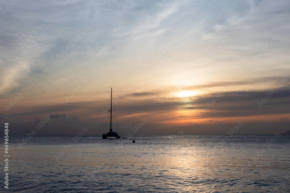 Catamaran yacht is under sunset sky. Mahe island, Seychelles
